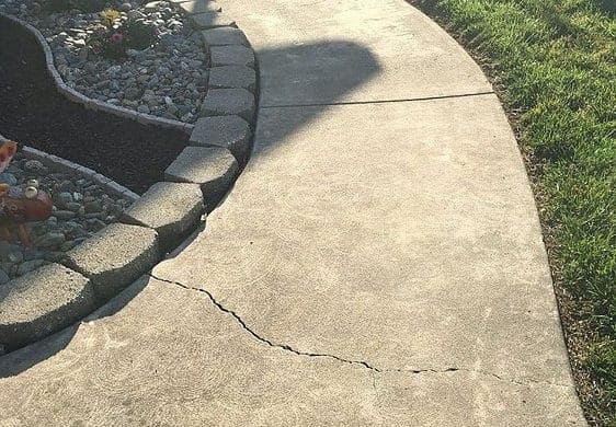 Pitted and stained bare concrete garage floor damaged by winter salt